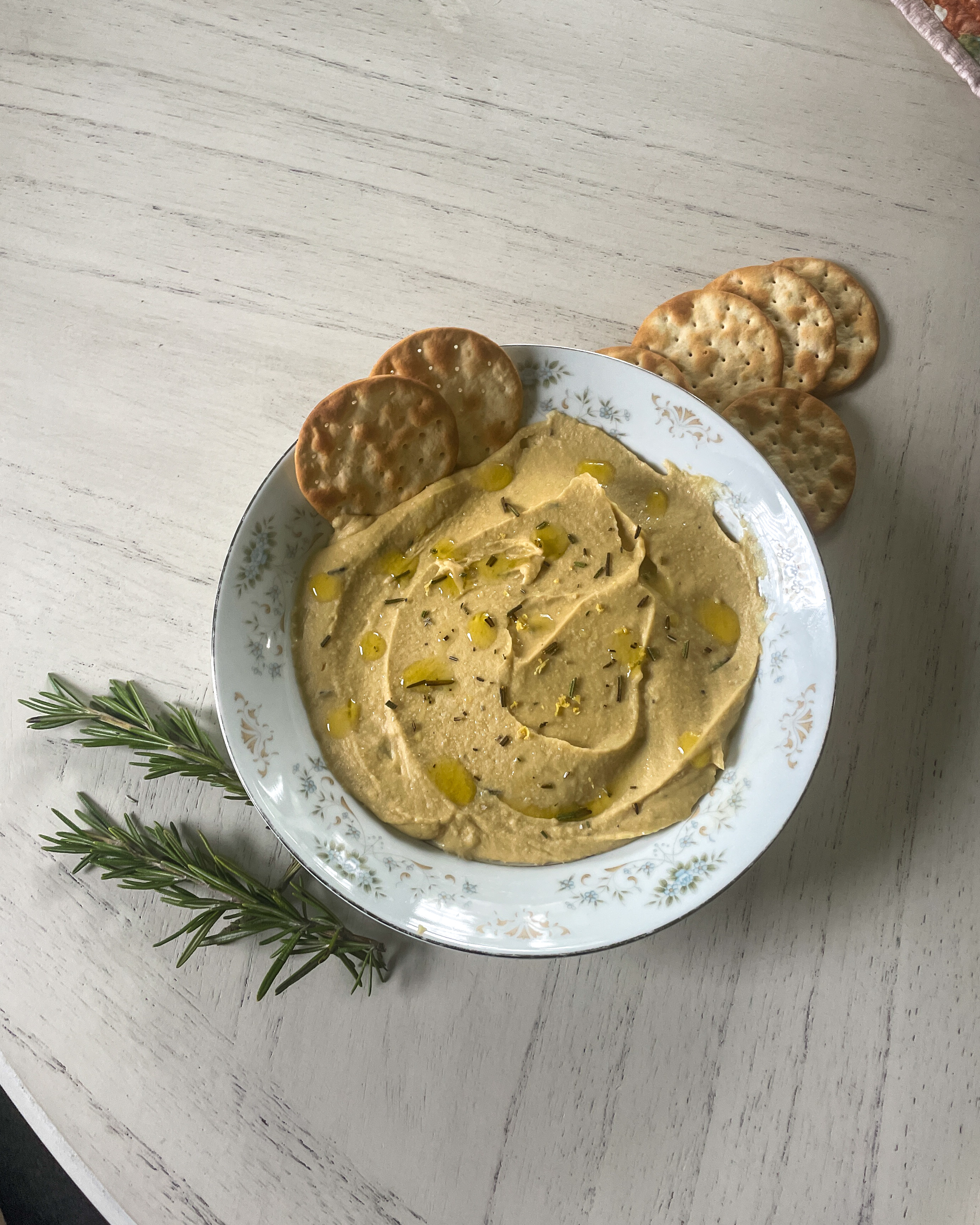 bowl of roasted rosemary hummus with crackers